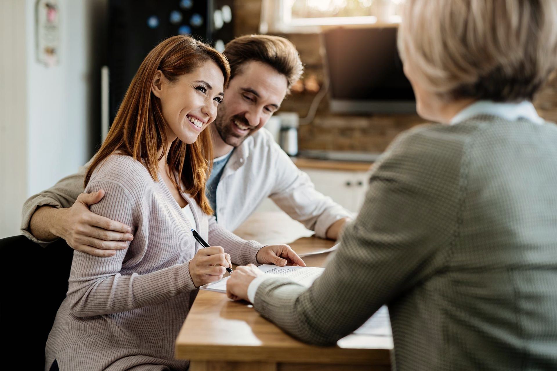 A man and a woman are sitting at a table talking to a woman.