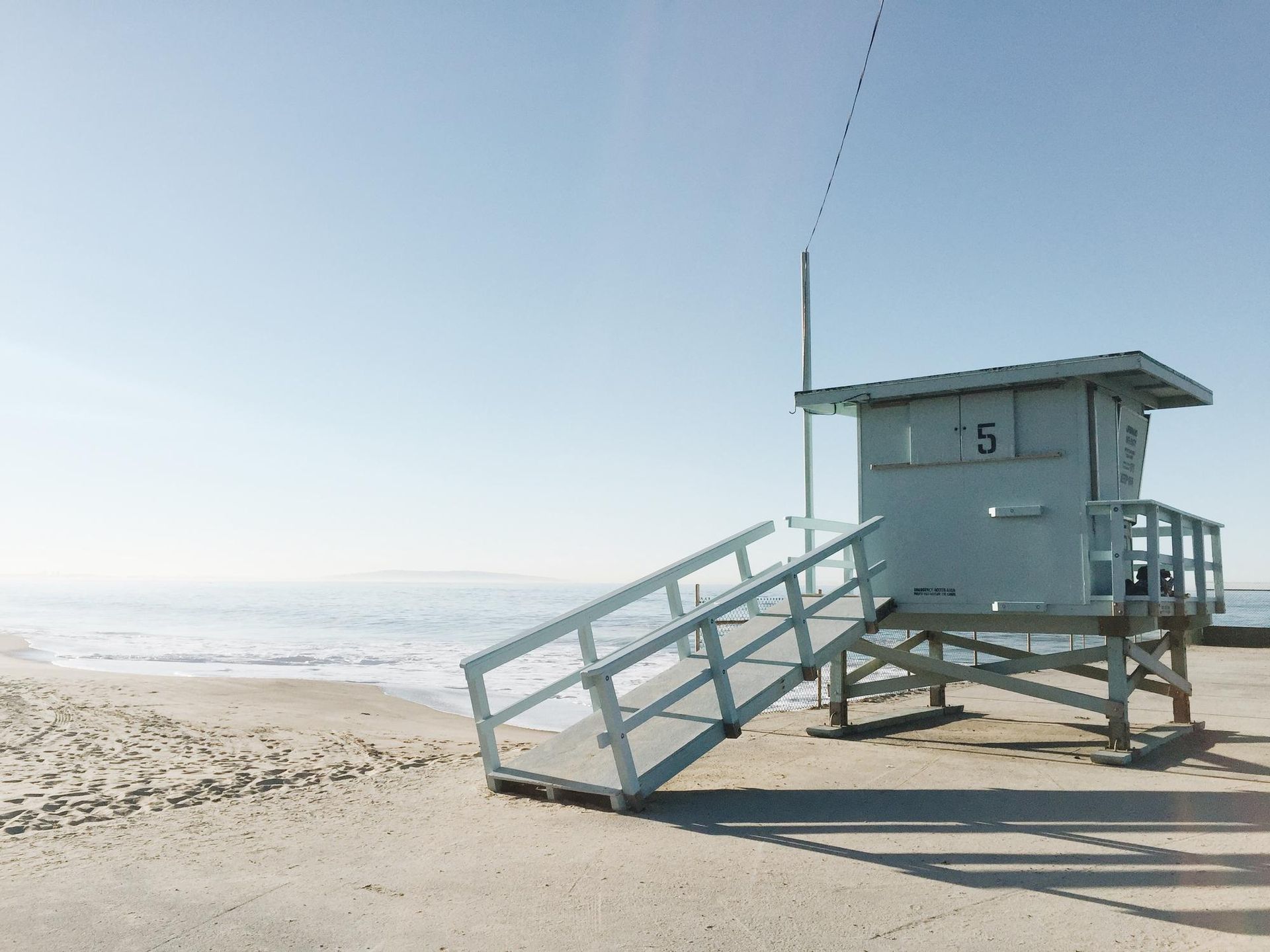 A lifeguard tower on a beach next to the ocean.