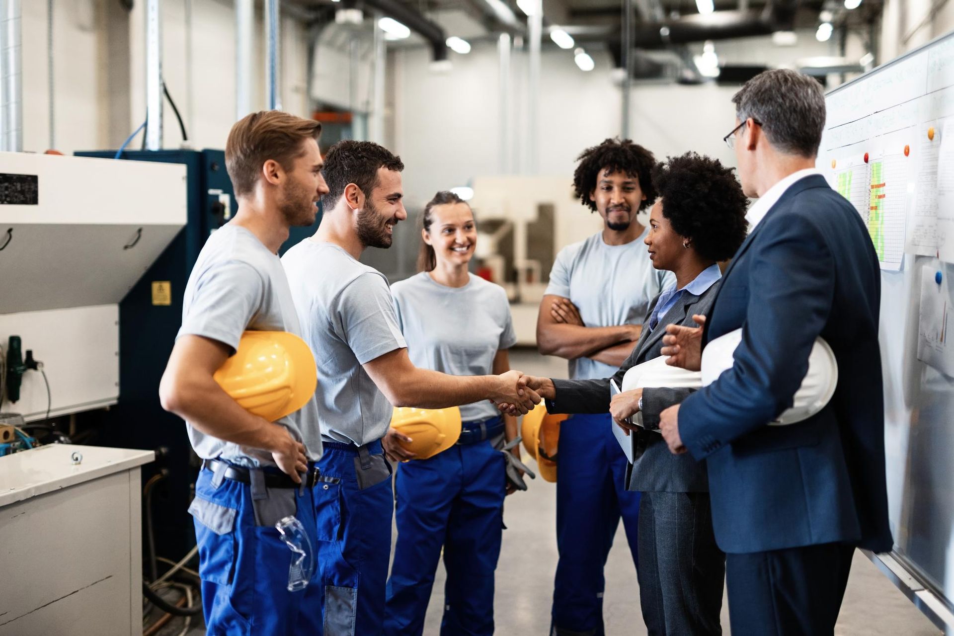A group of people are shaking hands in a factory.