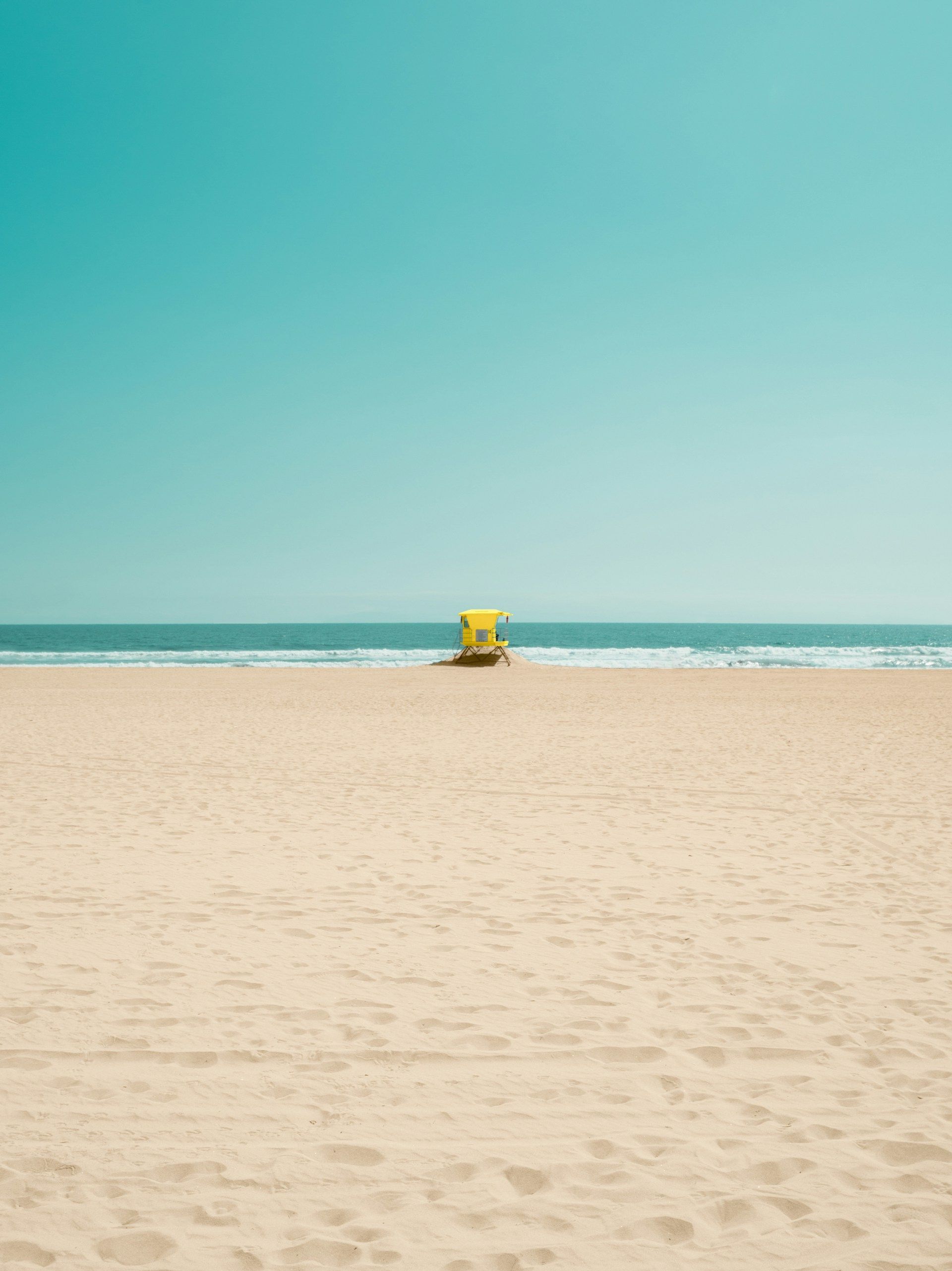 There is a yellow lifeguard tower on the beach.