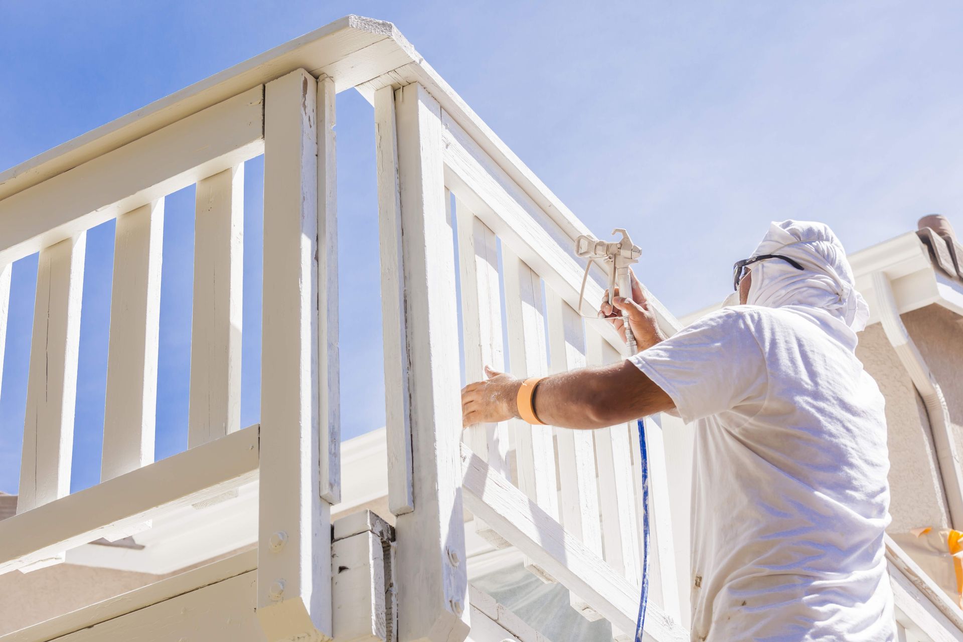 a man is painting a white railing on a house .