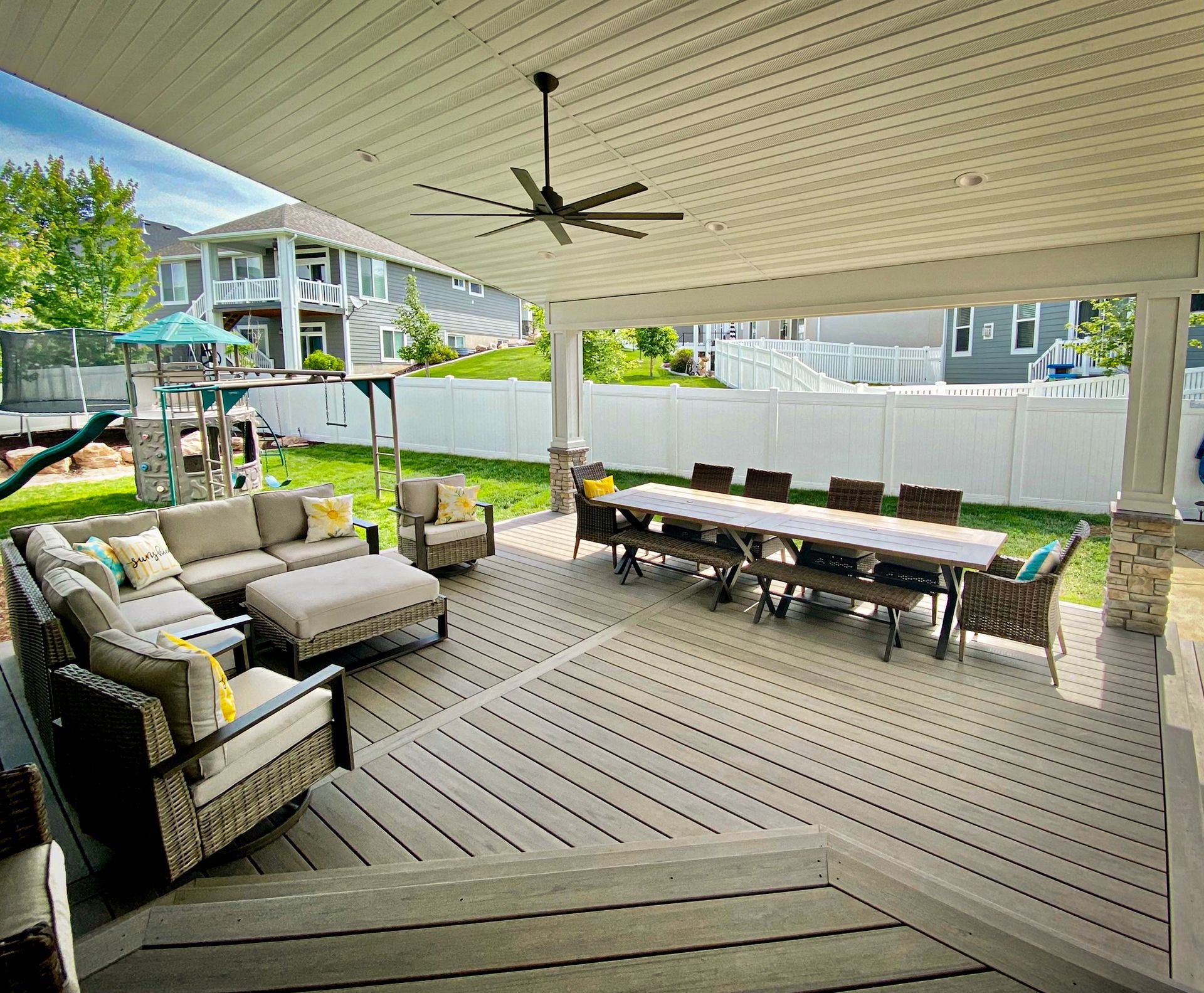A large covered patio with a table and chairs and a ceiling fan.
