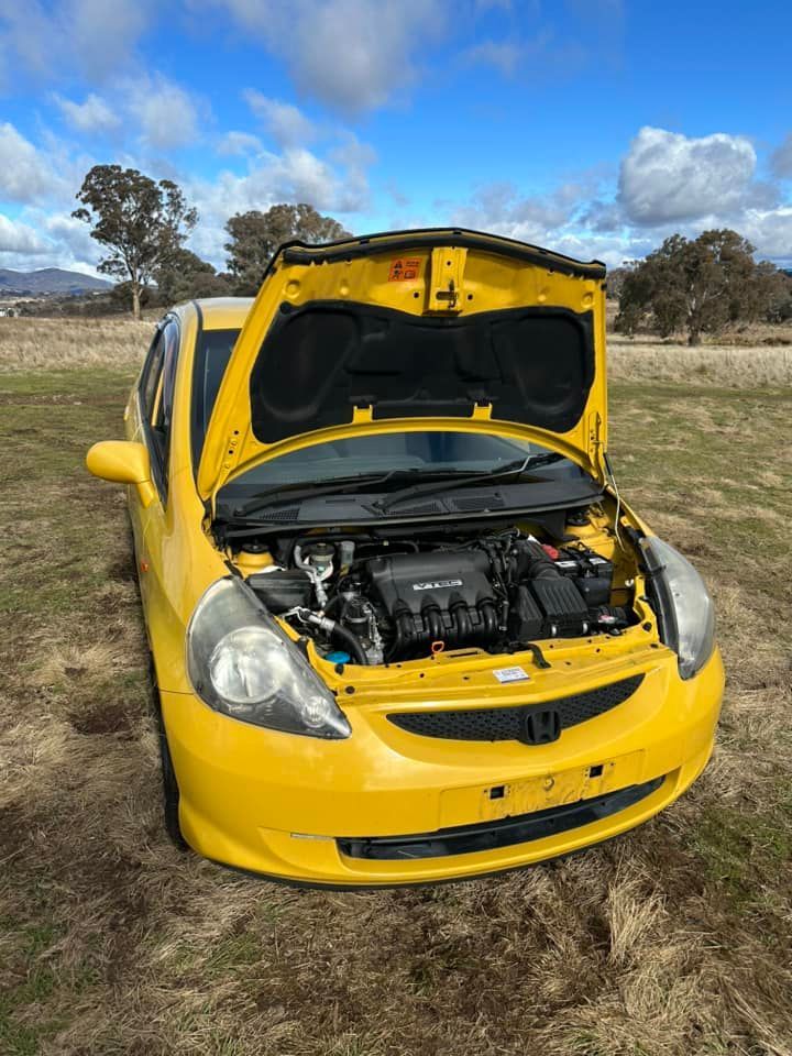 A Yellow Car With The Hood Up Is Parked In A Field — R N R Wrecking N Scrap Car Removal In Beard, ACT