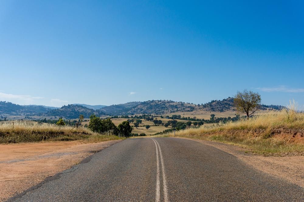 A Road Going Through a Desert Landscape With Mountains in the Background — R N R Wrecking N Scrap Car Removal In Beard, ACT