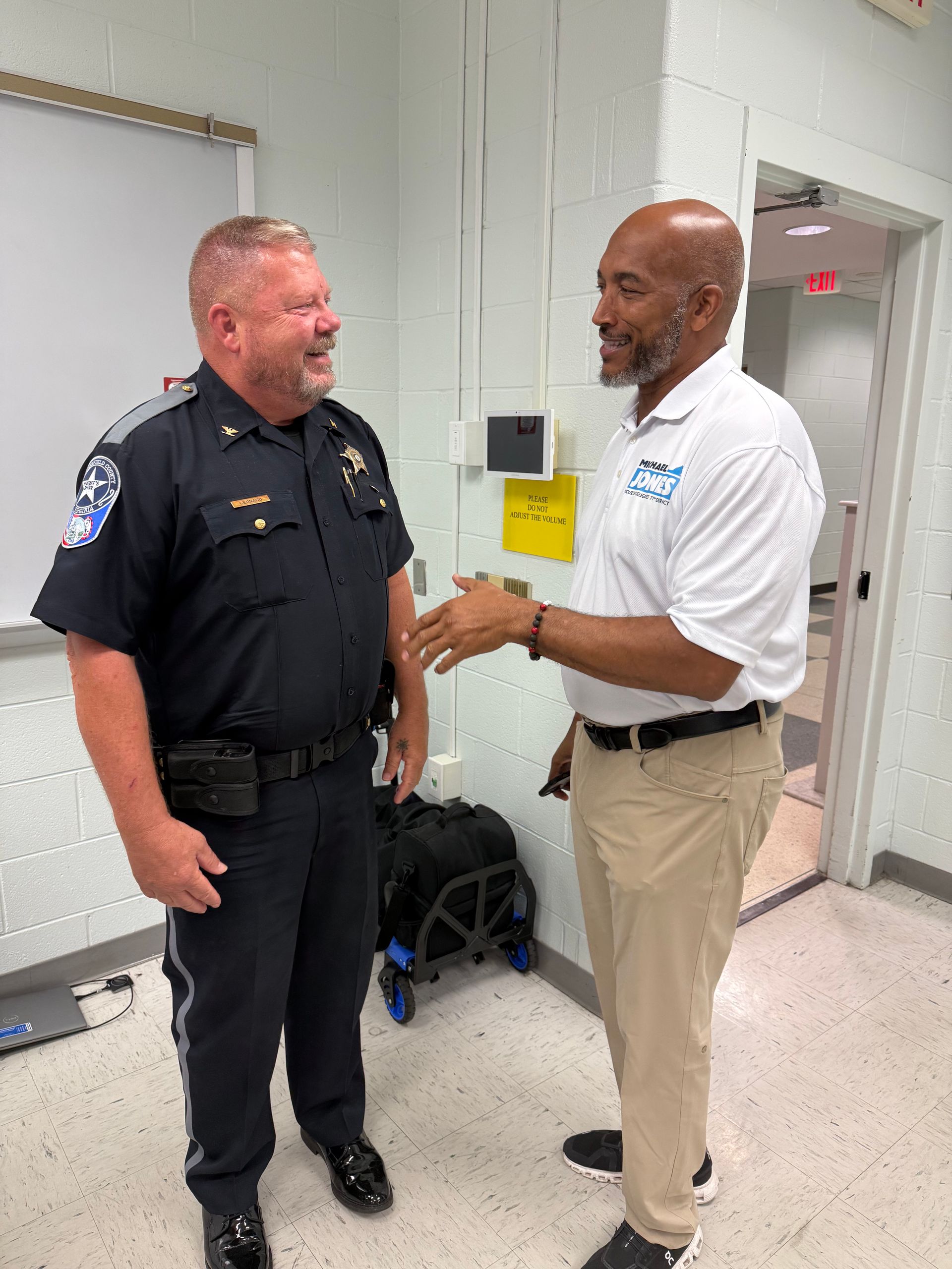 Person's hands writing with a pen on white paper on a white table. Wearing a gold bracelet and rings.