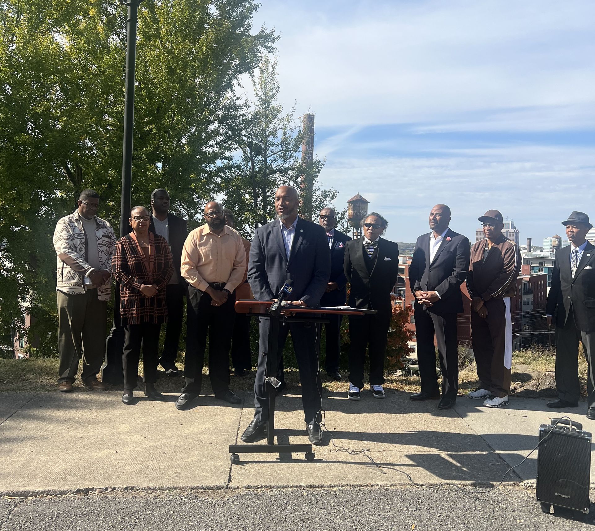 A man in a suit stands at a podium in front of a group of people