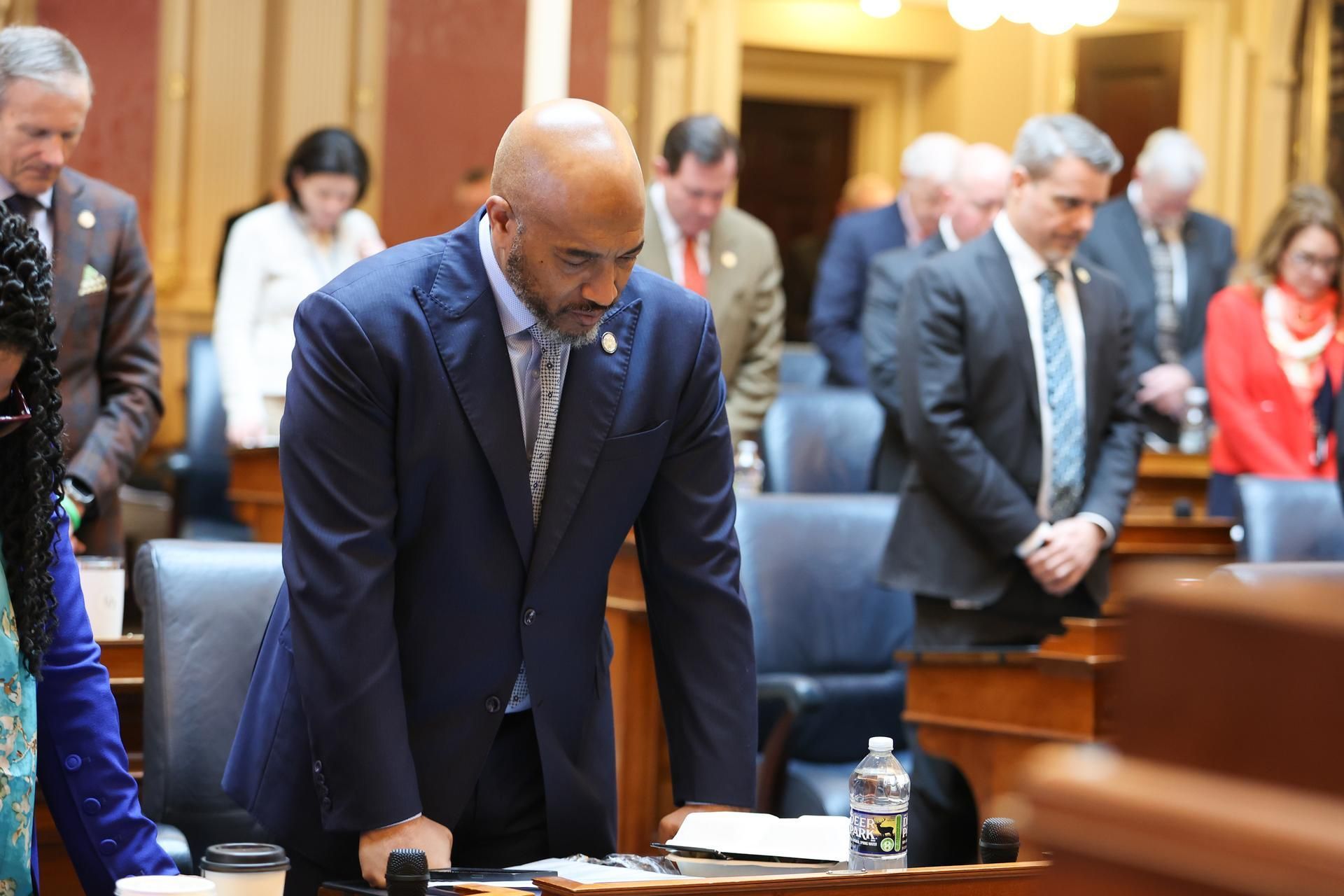 A man in a suit and tie is standing in front of a group of people.