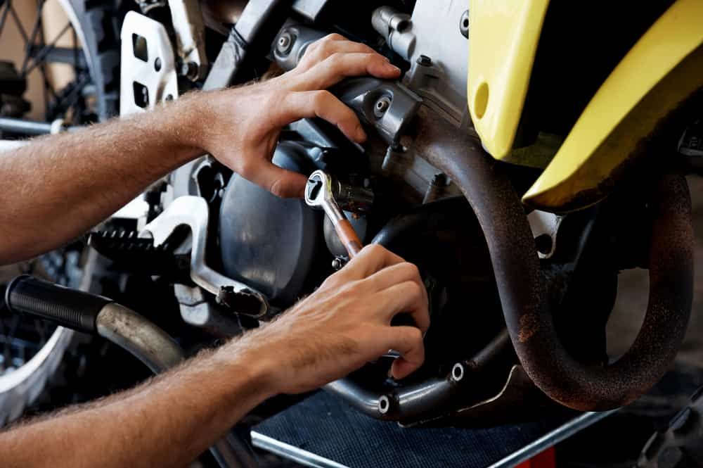 A Man Is Working On A Motorcycle With A Wrench — Strong Motors In Currajong, QLD