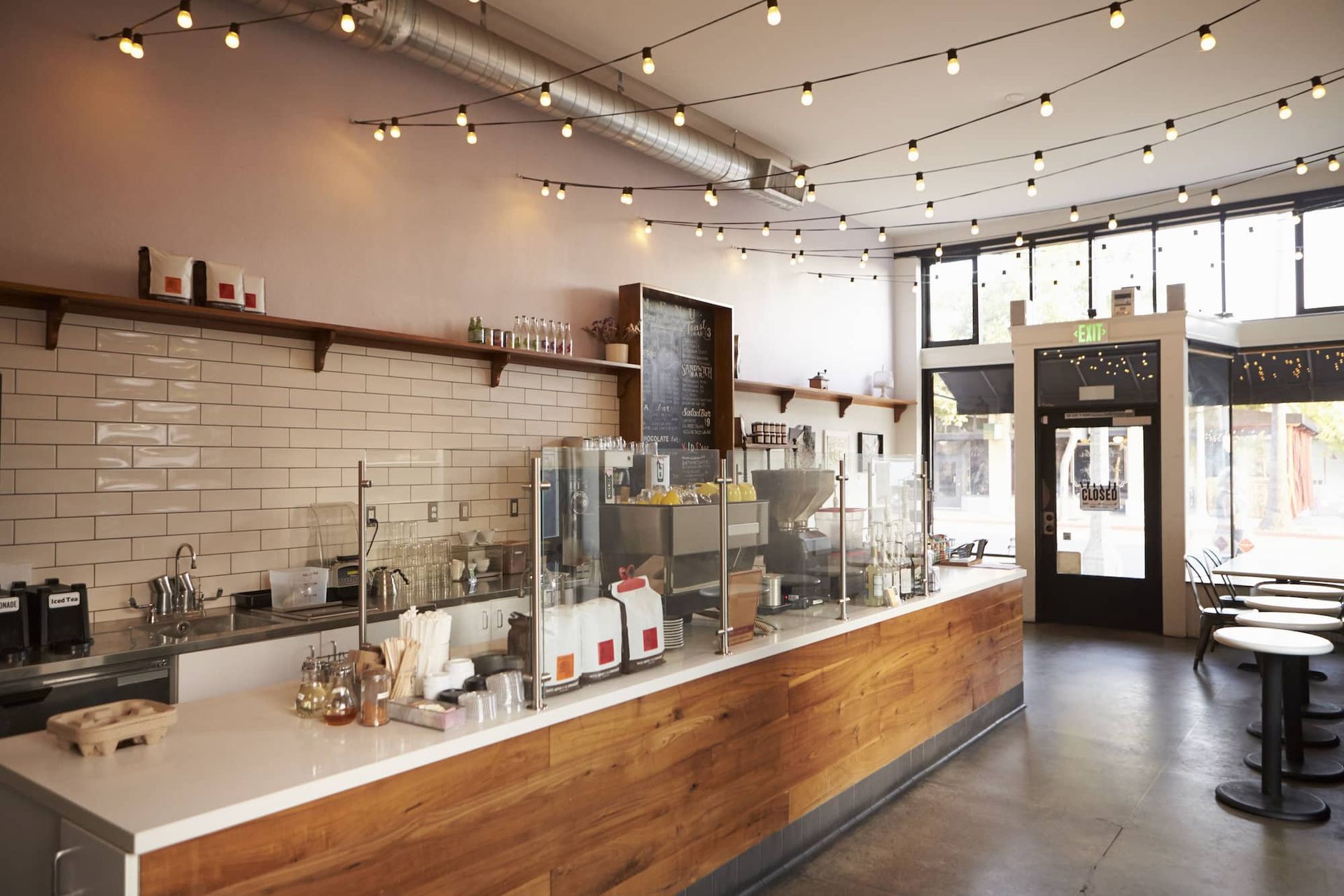 Coffee shop interior with light-strung ceiling, wood counter, and large windows.
