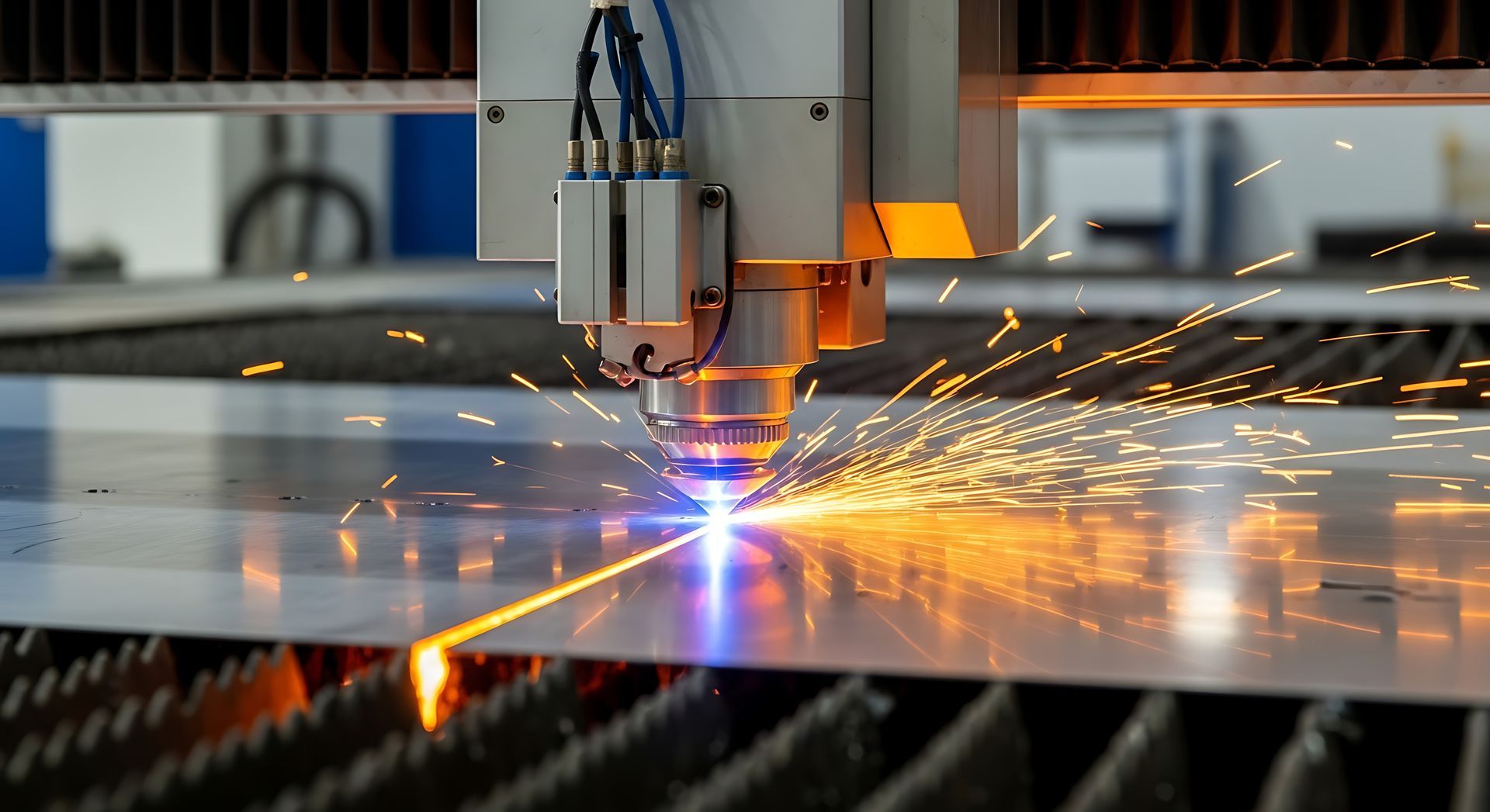 Laser cutter in action, cutting sheet metal with sparks and blue laser beam.