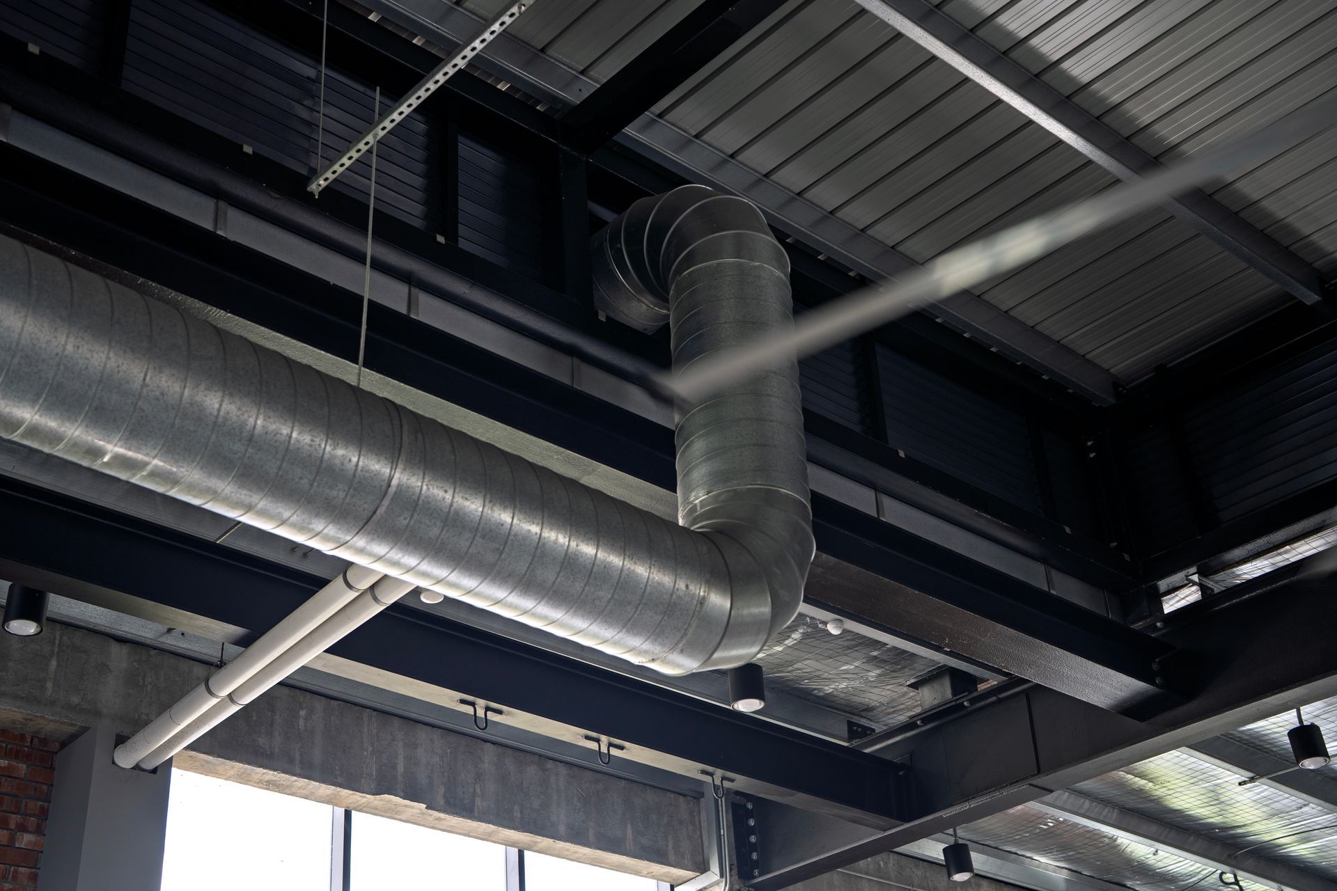 Galvanized ductwork against a dark ceiling with exposed beams. Galvanized ductwork against a dark ceiling with exposed beams.