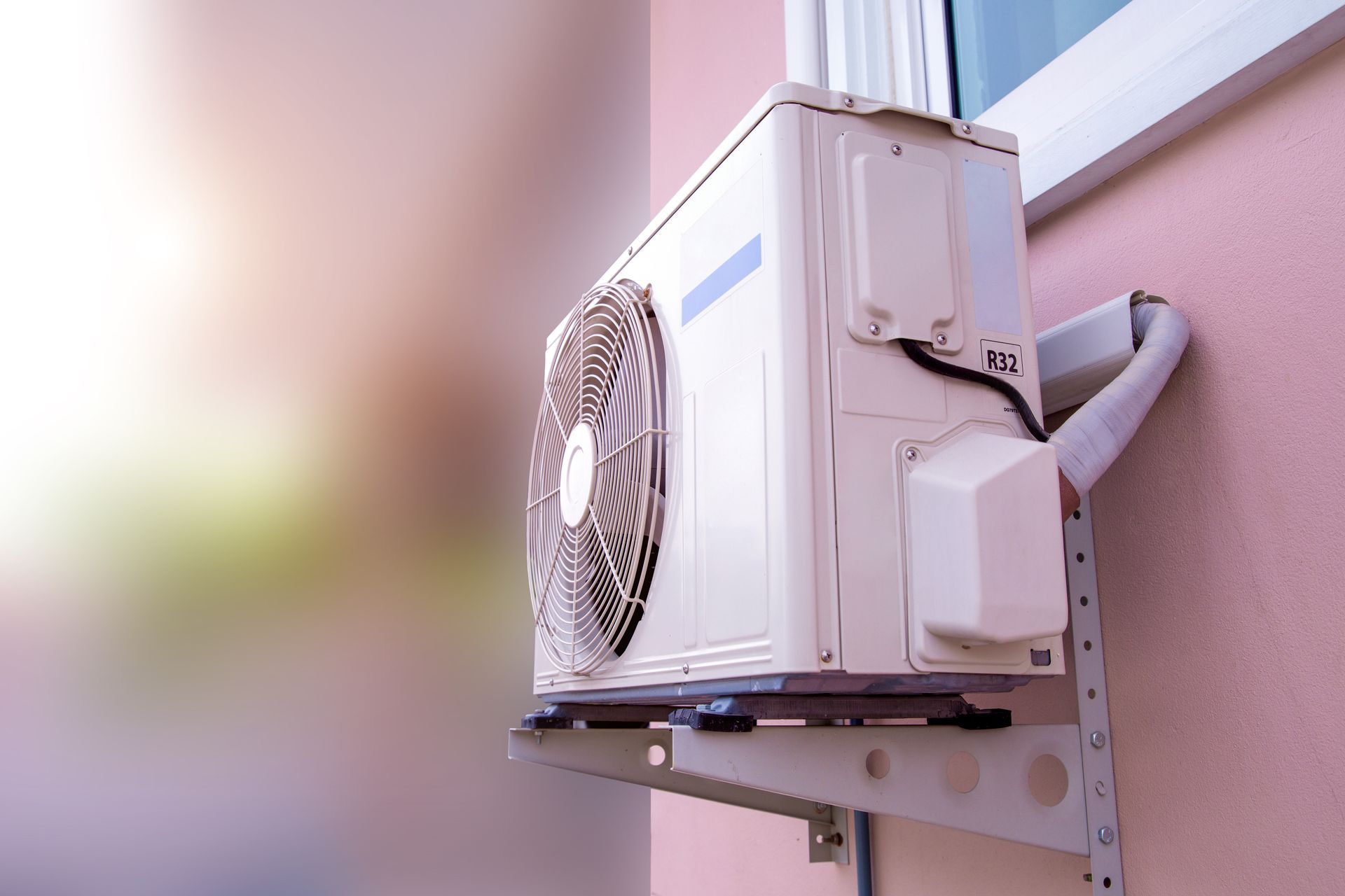 Air conditioning unit mounted on a pink exterior wall, near a window. Air conditioning unit mounted on a pink exterior wall, near a window.