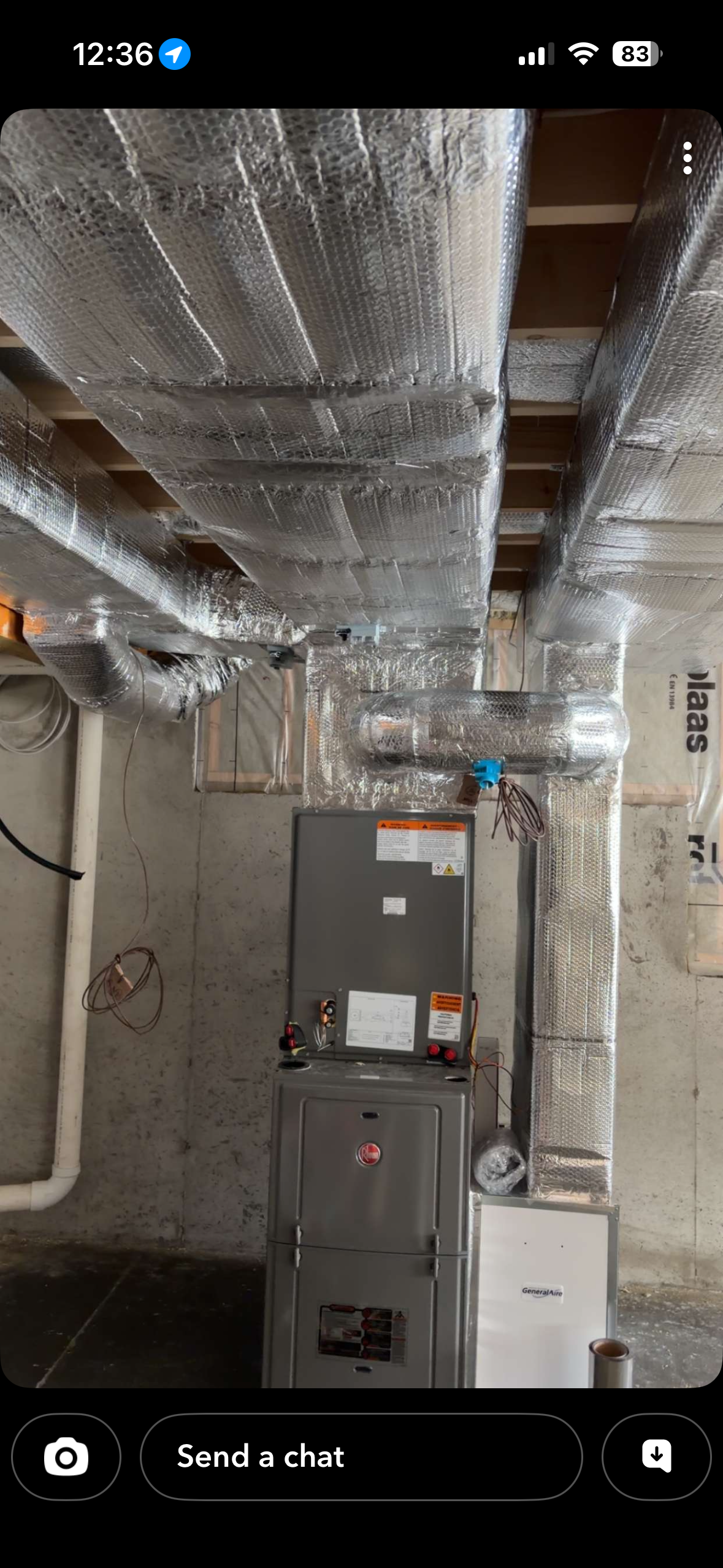 Furnace in a basement, with insulated ductwork overhead. Concrete walls and pipes are visible.