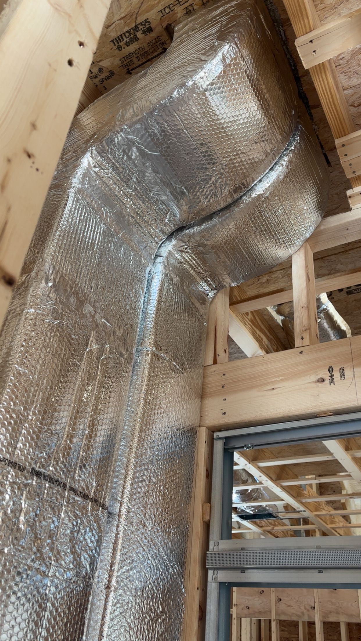 Construction site with silver reflective insulation covering a framed wall and ceiling.
