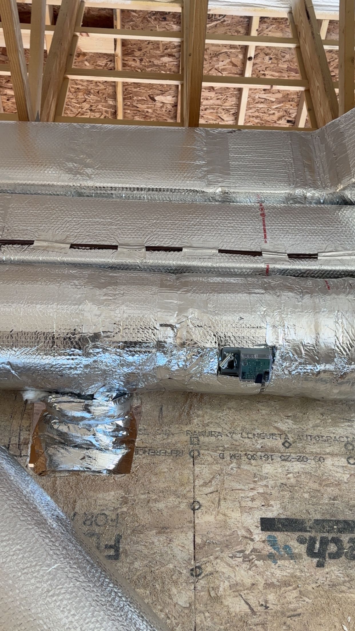 Construction site detail of plywood, insulation, and roof rafters.
