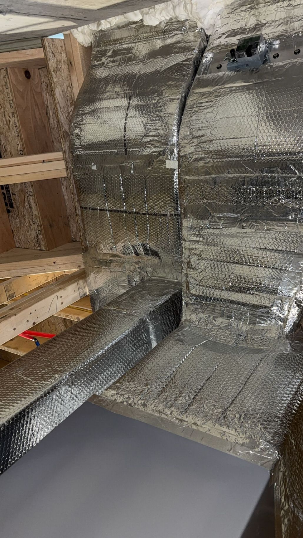 Shiny metal pipes and ductwork along a ceiling.