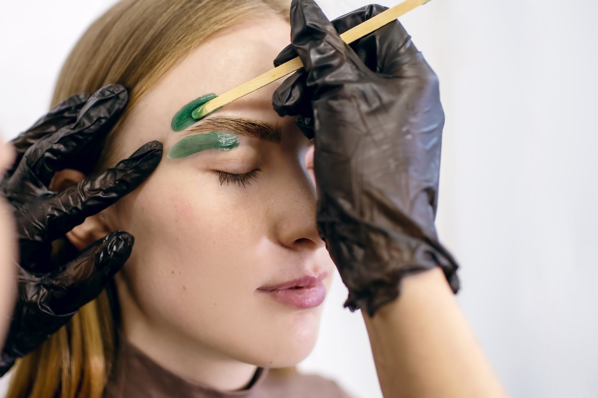 A woman is getting her eyebrows waxed in a salon.