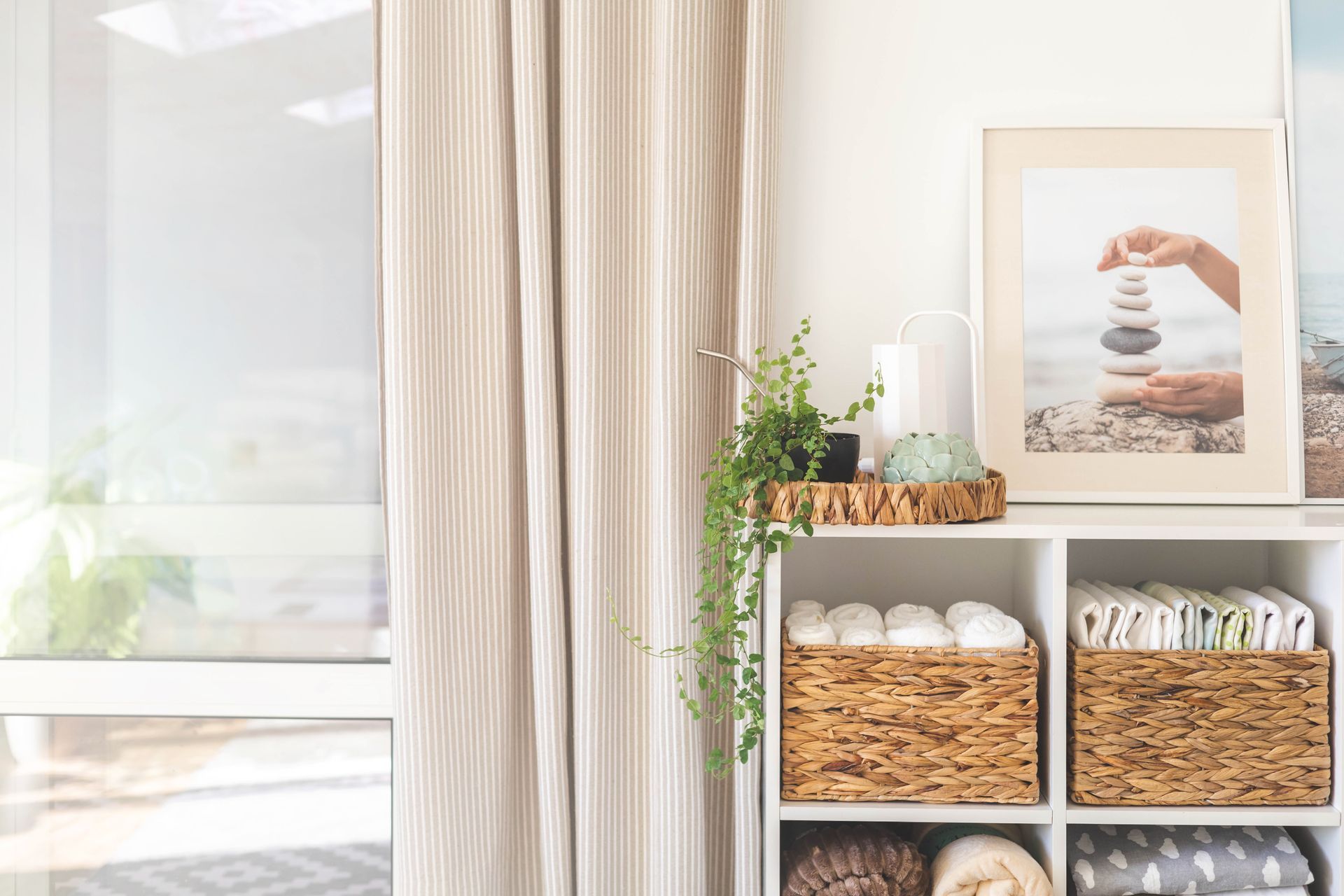 An organized shelf displaying neatly arranged rattan boxes filled with towels.