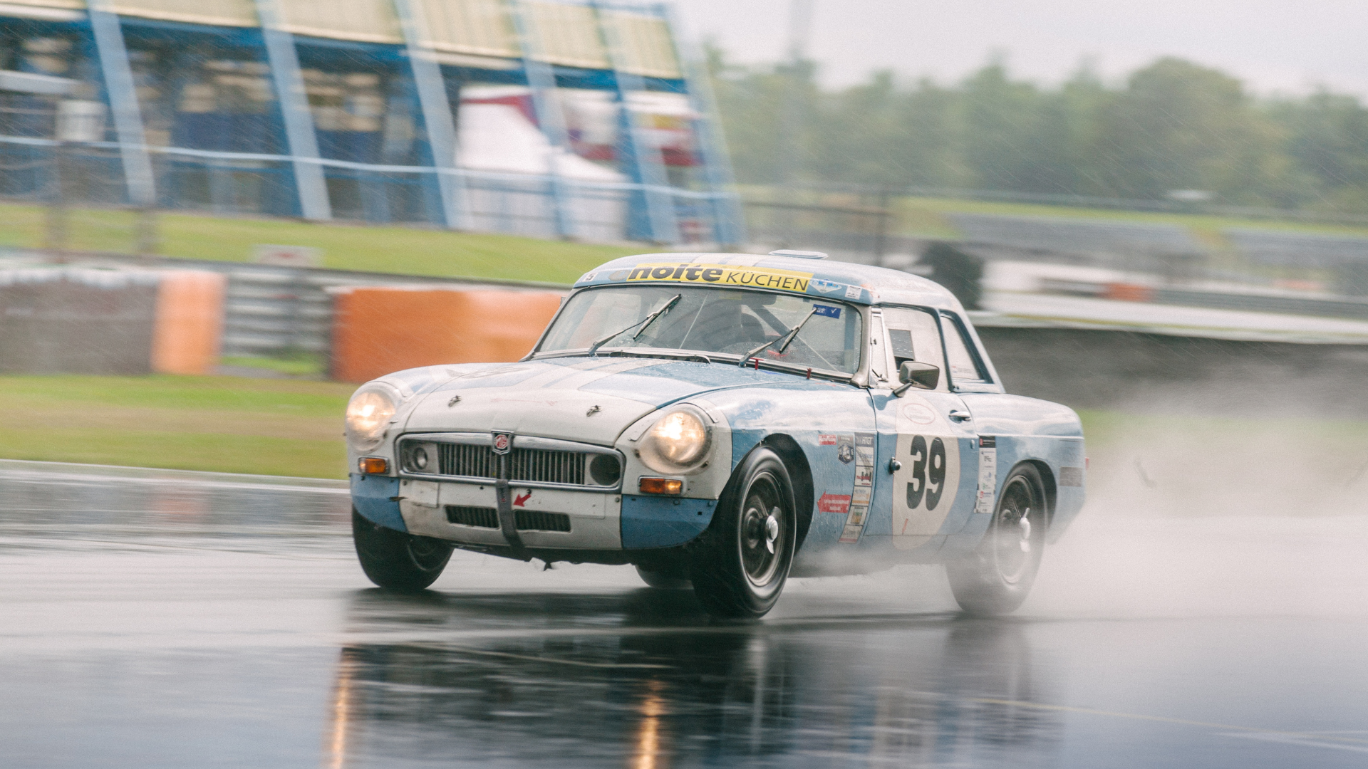 A racing car is driving on a wet track in the rain.