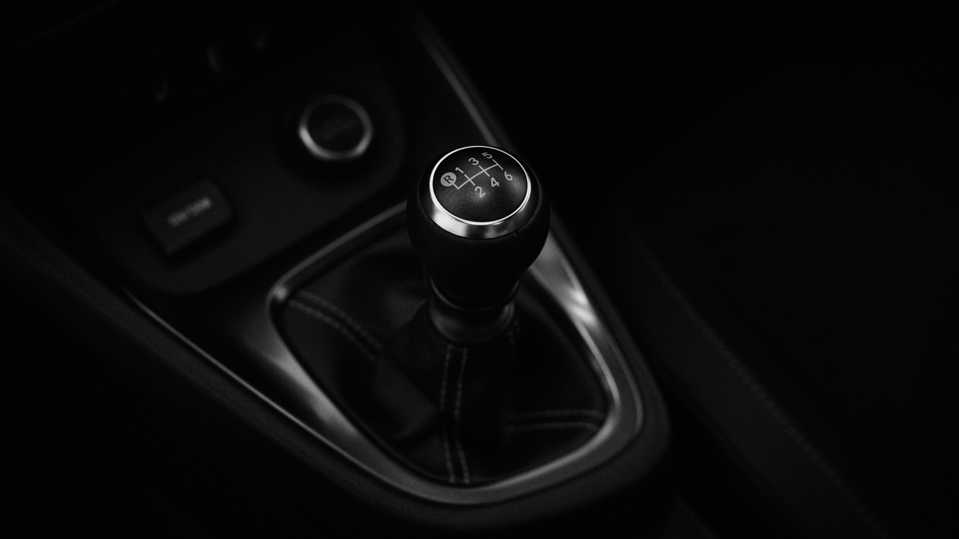 A close up of a car 's gear shifter in a dark room.