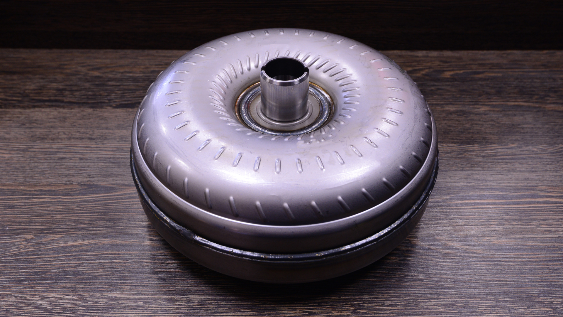 A metal container with a hole in the middle is sitting on a wooden table.