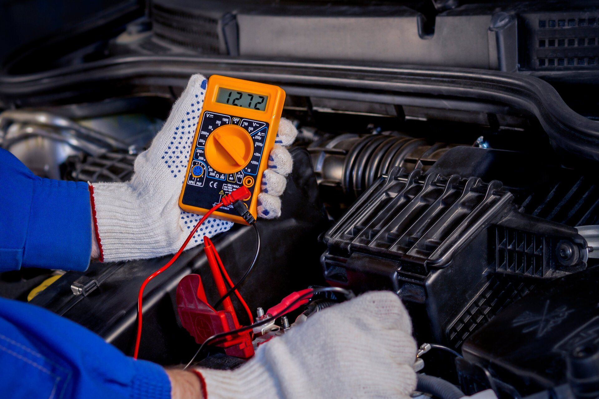 Mechanic inspecting a car’s engine with the hood open in a parking lot