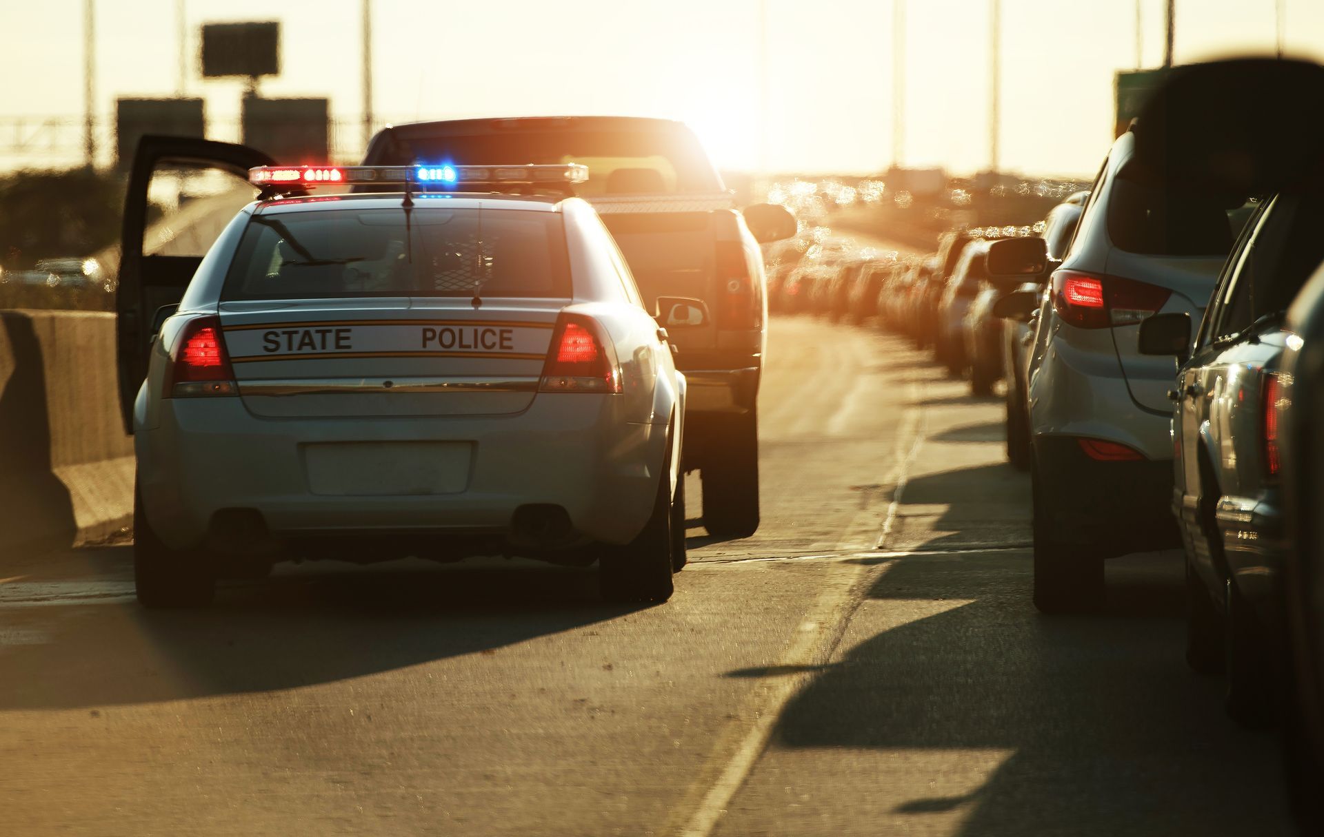 Police car with flashing lights in a traffic jam during sunset.