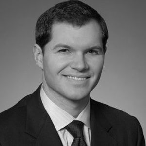 Man in suit, smiling slightly, headshot.