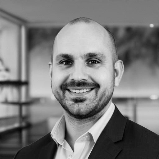 Man in a blazer smiles, looking at the camera.