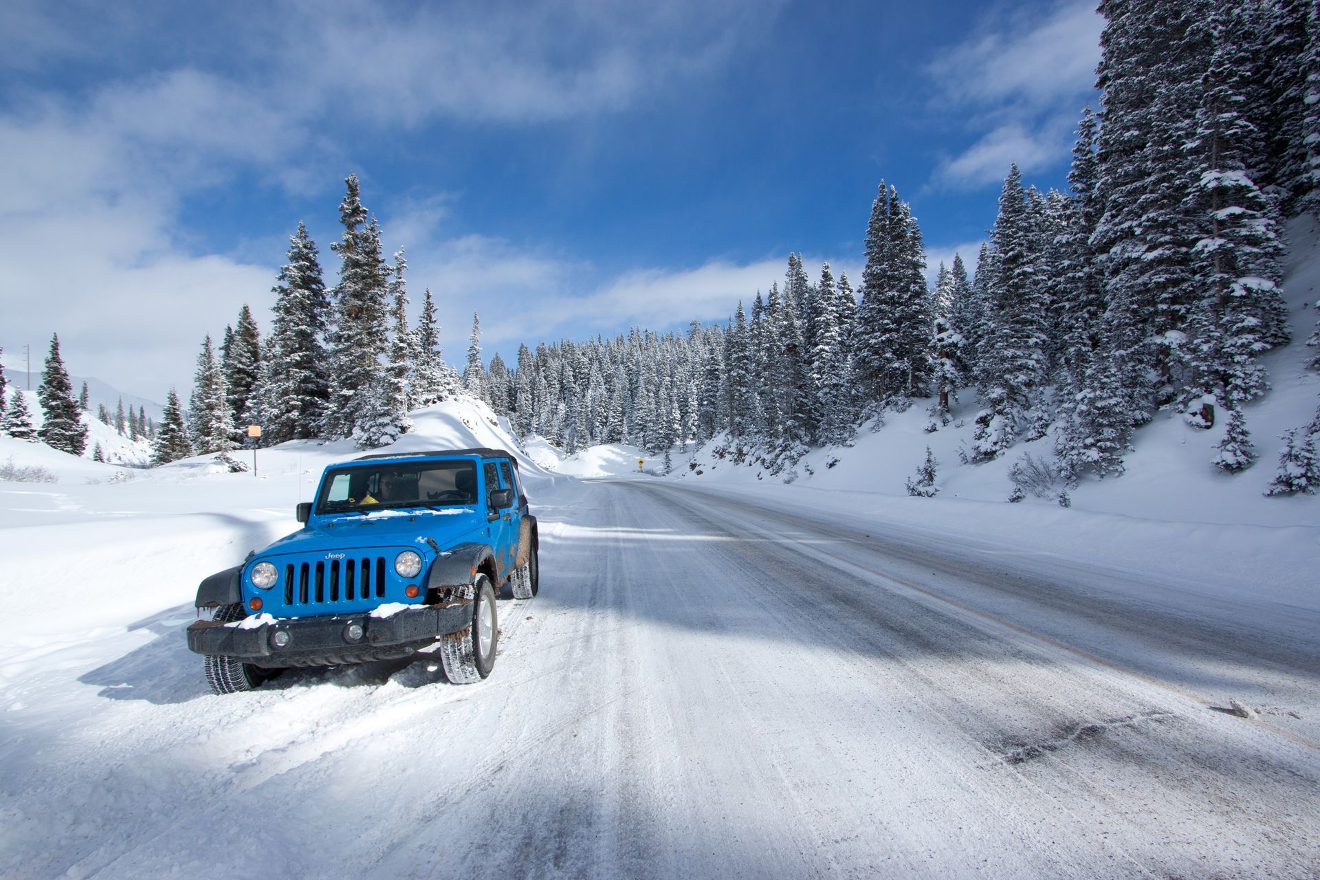blue-jeep-on-snowy-mountain-road