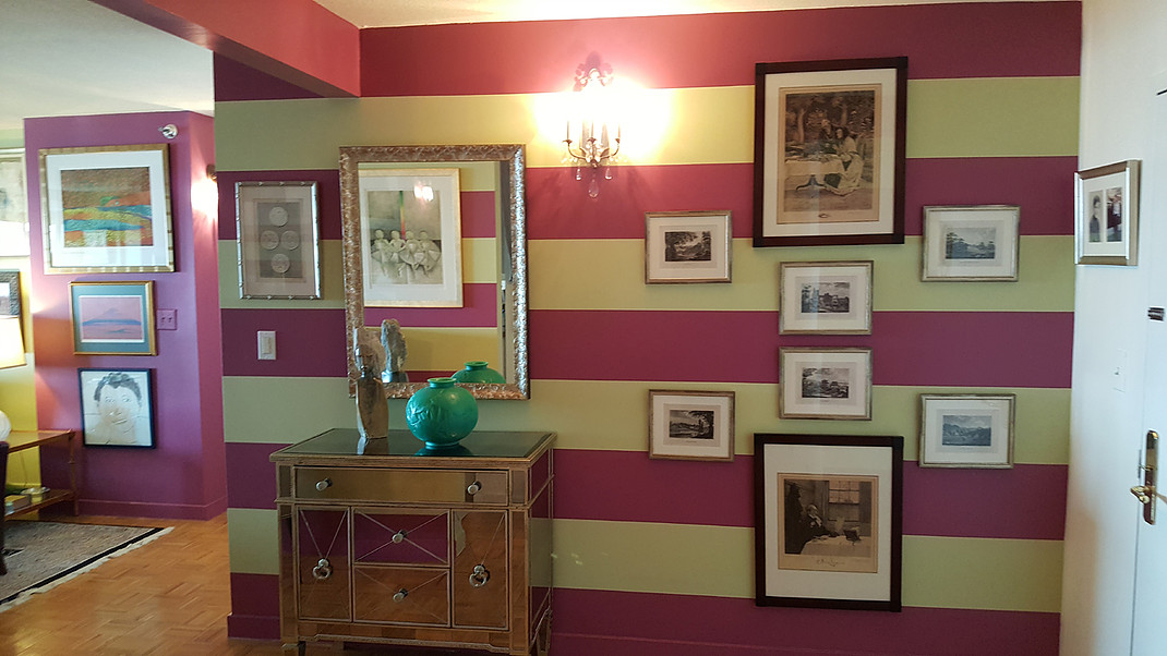 A hallway with striped walls and pictures on the wall.
