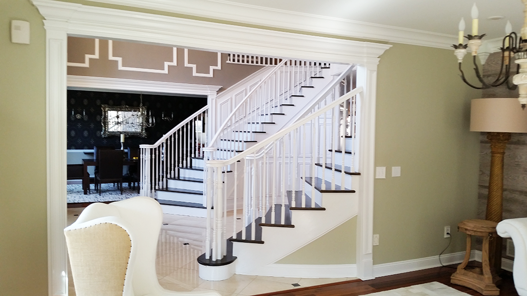 A living room with a staircase leading to a dining room.
