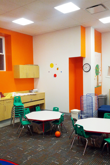 A classroom with tables and chairs and a clock on the wall