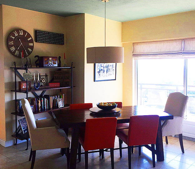 A dining room with a table and chairs and a clock on the wall