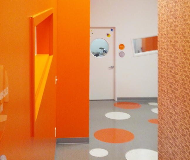 A hallway with orange walls and circles on the floor