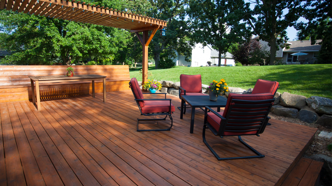 A wooden deck with a table and chairs under a pergola