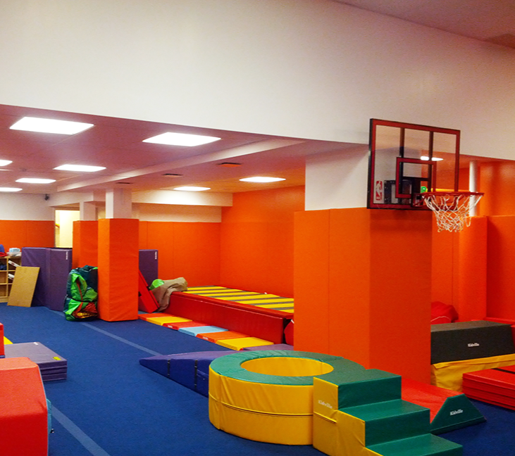A gym with orange walls and a basketball hoop