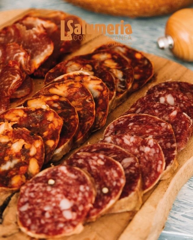 Salumi affettati su un tagliere di legno; primo piano che mostra le consistenze e i colori.