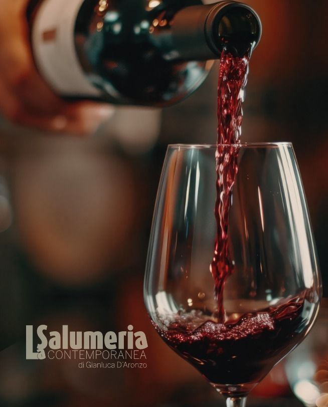 Vino rosso versato in un bicchiere trasparente, in un ambiente interno.