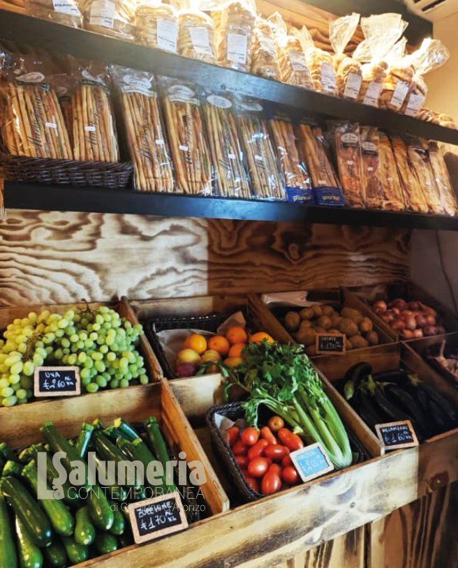 Prodotti ortofrutticoli e prodotti da forno confezionati esposti su scaffali di legno in un negozio.