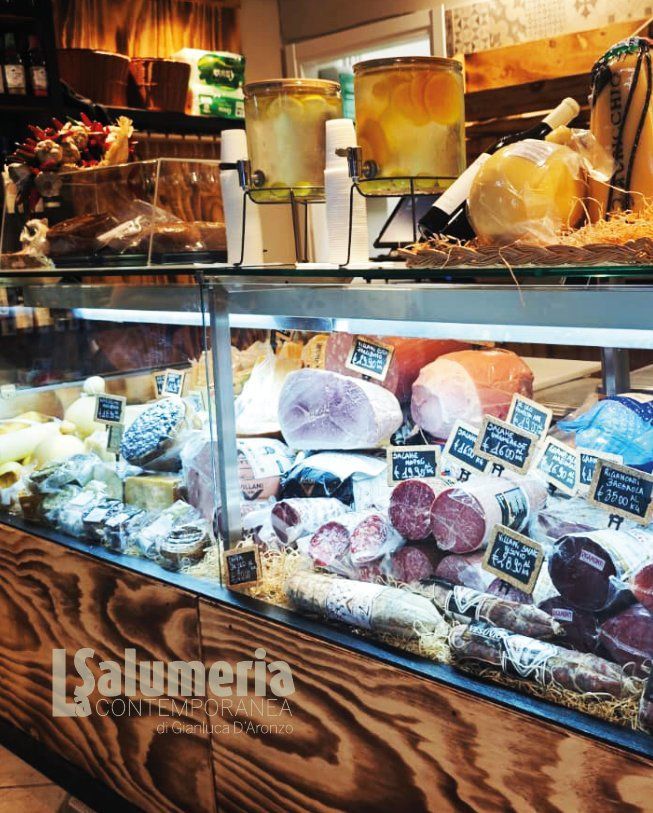 Vetrina piena di formaggi e salumi in un negozio.