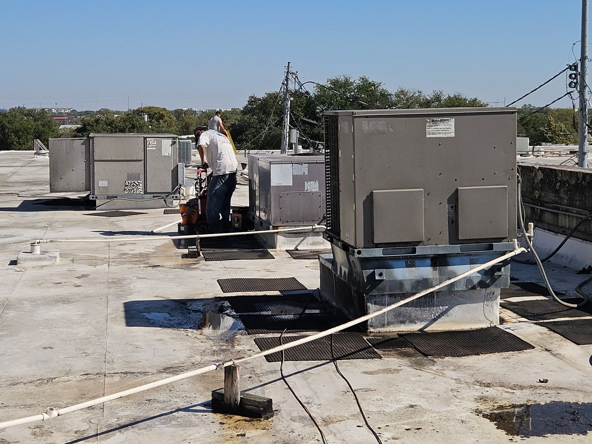 HVAC technician working on rooftop air conditioning units on a sunny day.