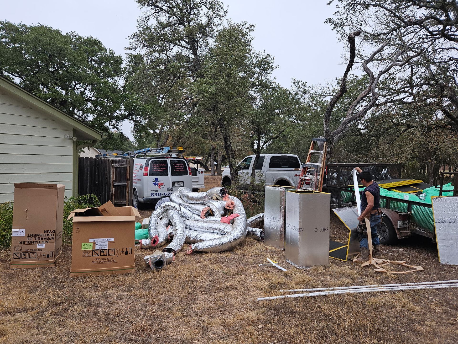 Backyard with HVAC work: trucks, materials, ladder, and person near house.