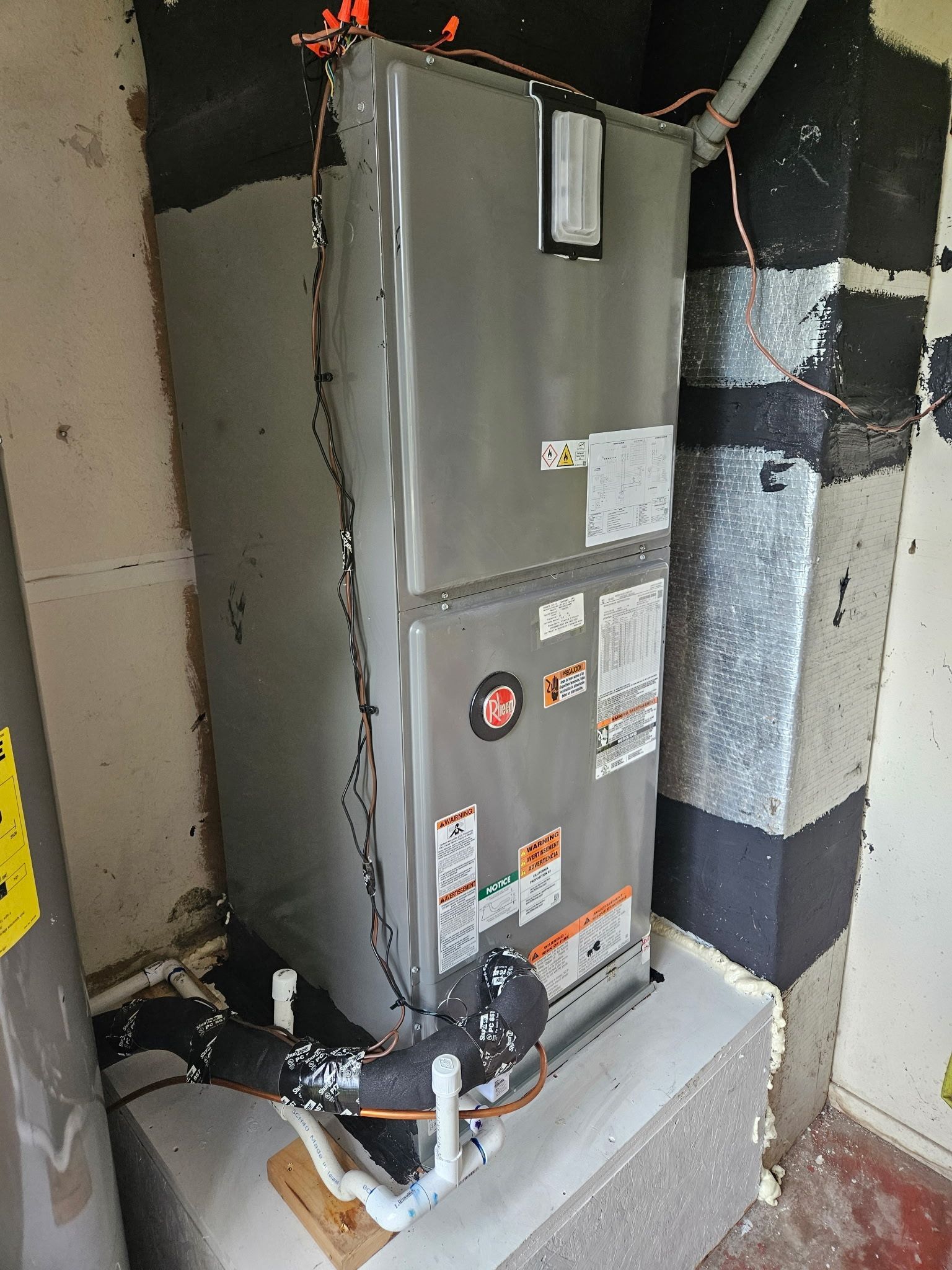 HVAC unit inside a utility room next to a water heater and ductwork. Gray and silver appliances.