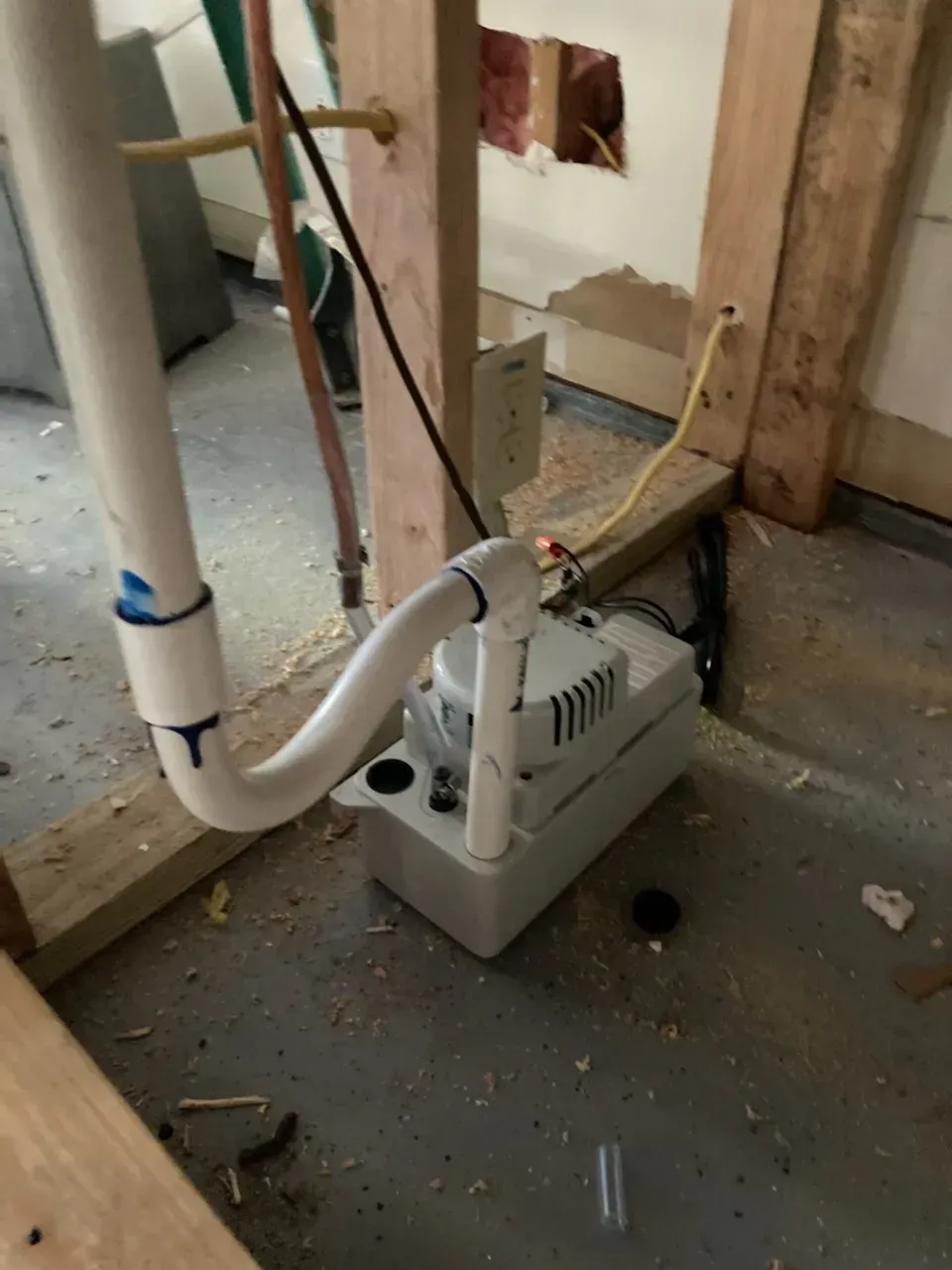 A white pump is sitting on the floor next to a pipe
