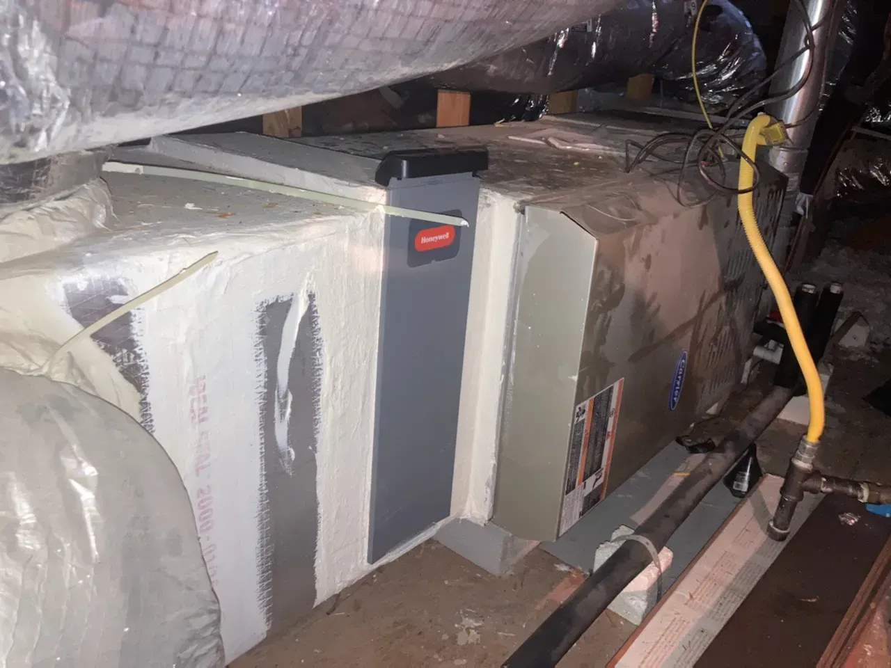 A gray box with a red button on it is sitting on a wooden floor.