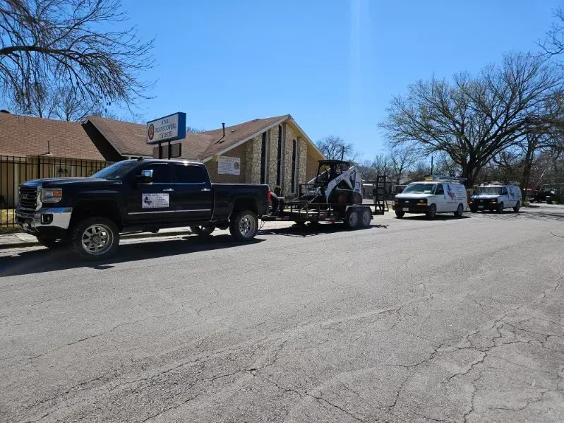 A row of trucks are parked on the side of the road in front of a building.