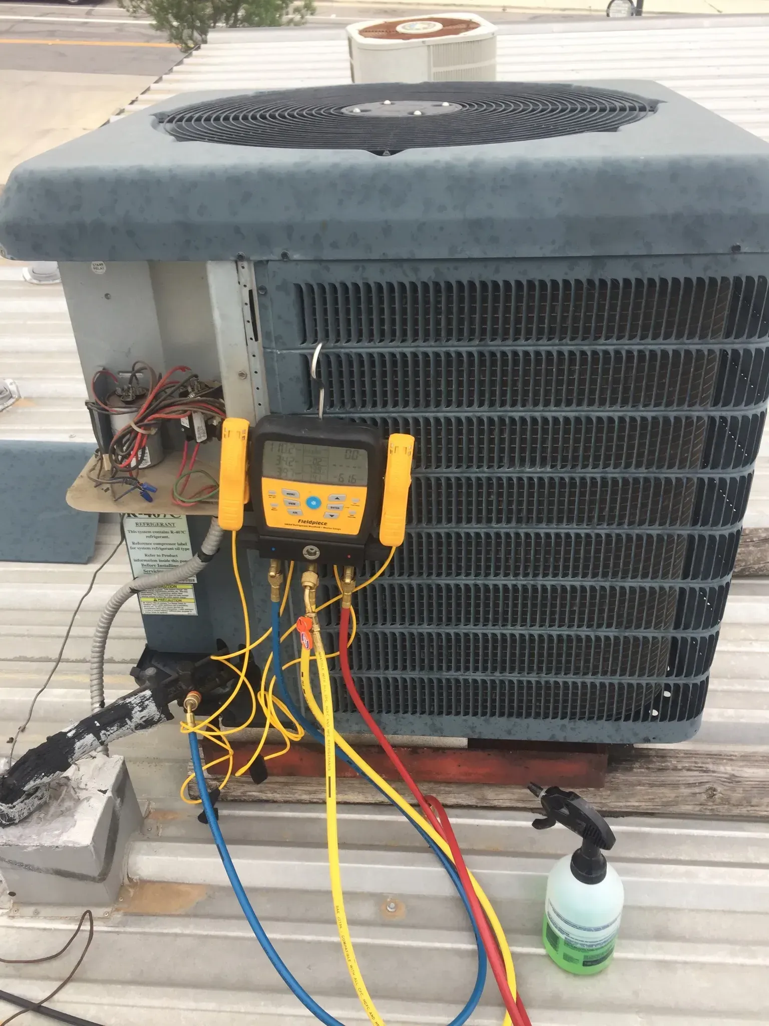 An air conditioner is being serviced on the roof of a building.