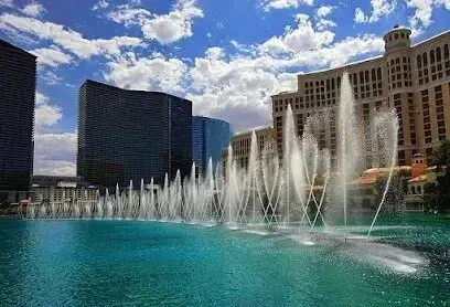 Mobile Detailing-Fountains erupt in front of the Bellagio Hotel, Las Vegas. Bright blue water, clear sky, and modern buildings.