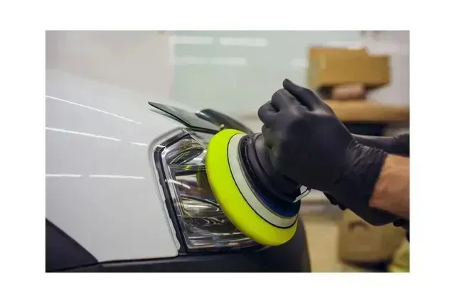 Mobile Detailing - A person is polishing a white car with a yellow polishing pad.